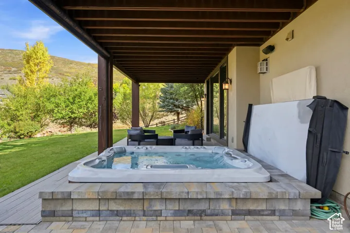 Covered patio with a built-in spa, paver patio, and stone veneer surround