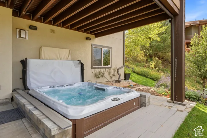 Spa with cover lifter, paver surround, and composite decking under a covered patio