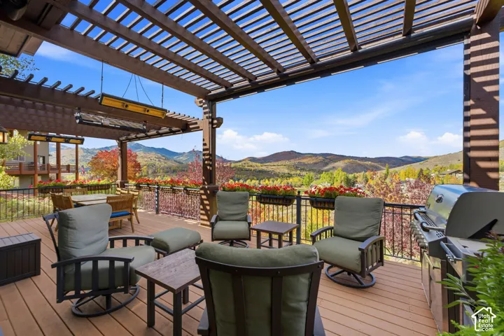 Expansive outdoor deck featuring a wood-finish pergola, built-in overhead heaters, durable composite decking, and decorative metal railings