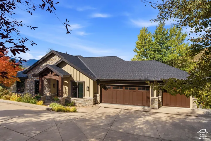 Stone and vertical siding exterior with a dark shingle roof