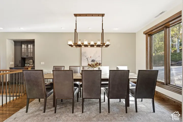 Dining area with wood-finish flooring, a built-in wet bar featuring dark cabinetry, and a large window with natural wood trim