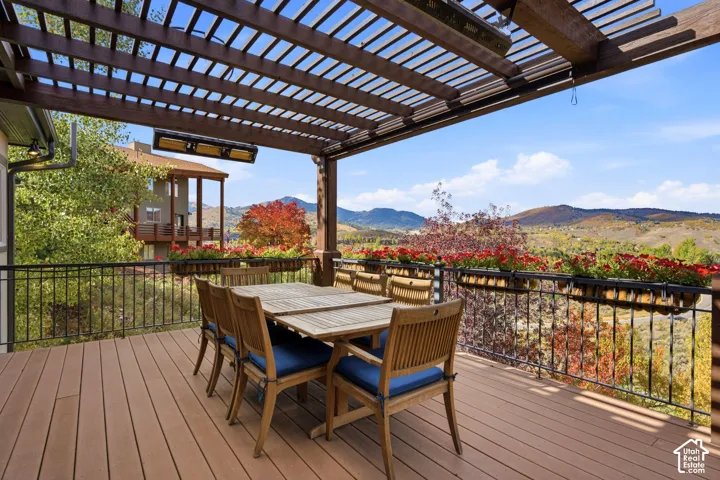 Expansive deck featuring a wooden slat pergola, composite decking, and wrought iron railings