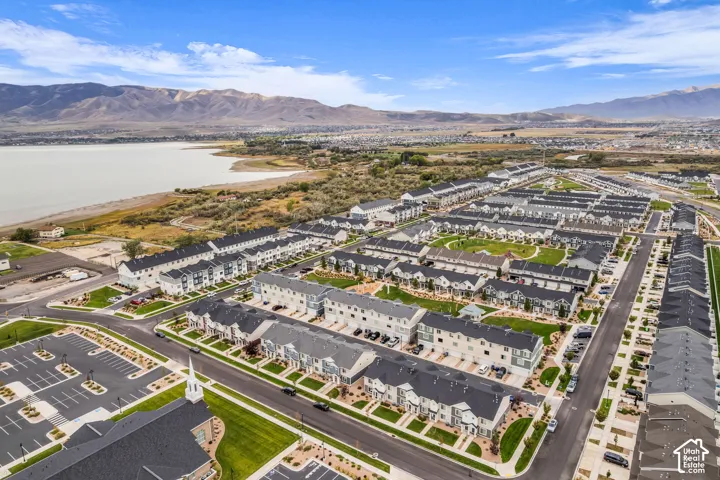 Expansive community with varied architectural styles, manicured common green spaces, and a prominent lake backdrop