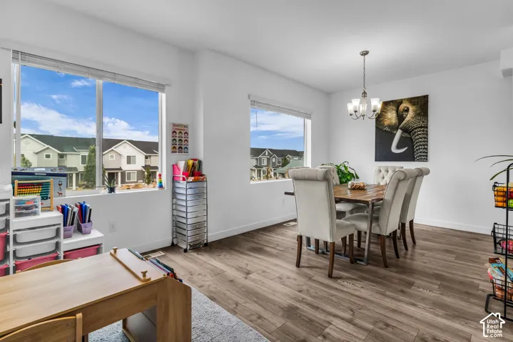 Spacious dining area featuring wood-finish flooring, multiple windows, and a built-in chandelier