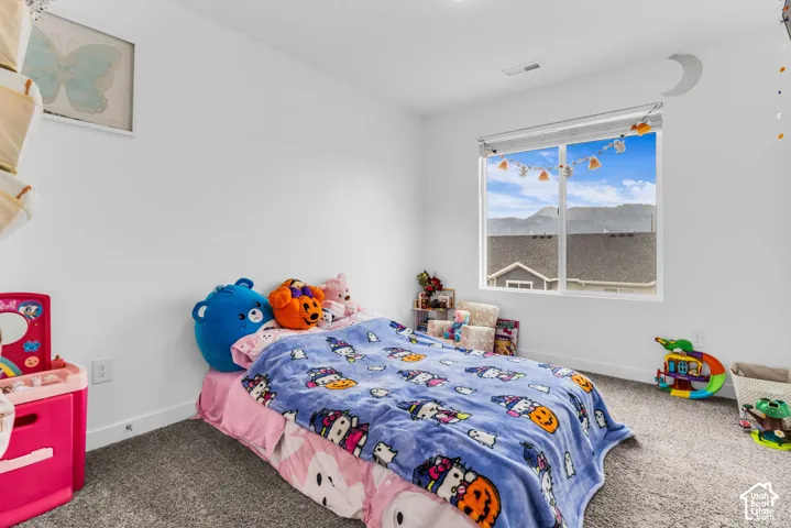 White walls with a window providing natural light, gray carpet flooring, and white trim