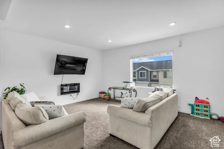 Recessed lighting, wall-mounted television, wall-mounted electric fireplace, single pane window, and carpeted flooring