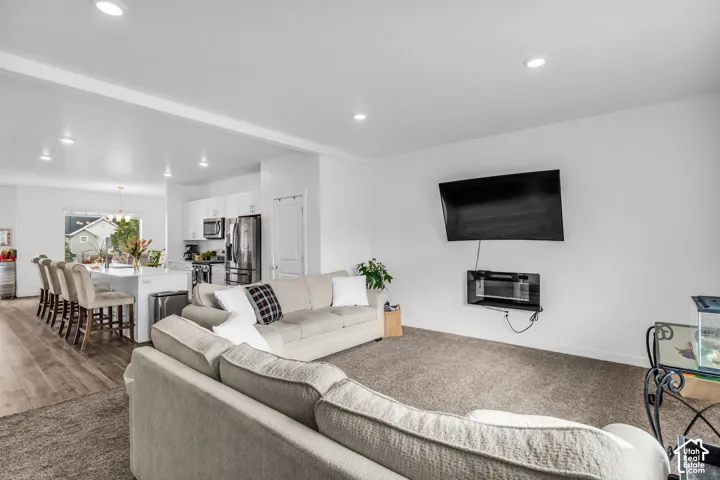 Open-concept living area with recessed lighting, wood-finish flooring, and white cabinetry