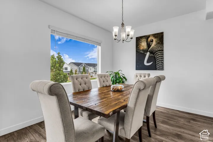 Wood-finish flooring paired with white walls, a multi-light chandelier, and a large window
