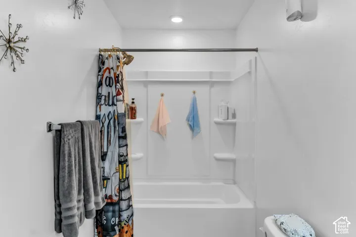 White tub and shower combination with integrated shelving