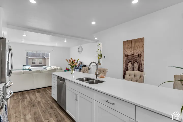 Kitchen island with white countertops, stainless steel sink, and integrated dishwasher