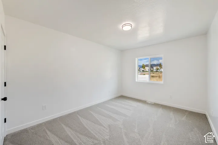 Neutral-toned carpeting, white walls, and a window with white trim
