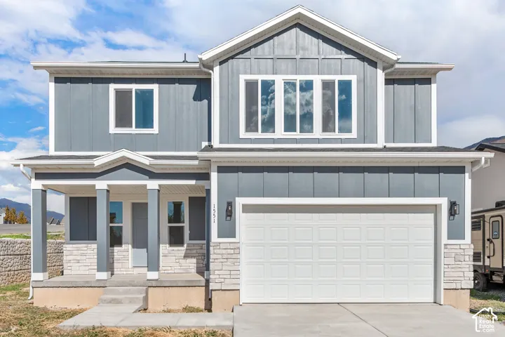 Contemporary two-story exterior with board and batten siding, stone facade accents, covered porch, multiple windows, and an attached two-car garage