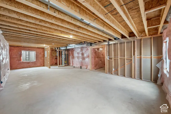 Unfinished basement featuring exposed wood joists, concrete flooring, and framed interior walls