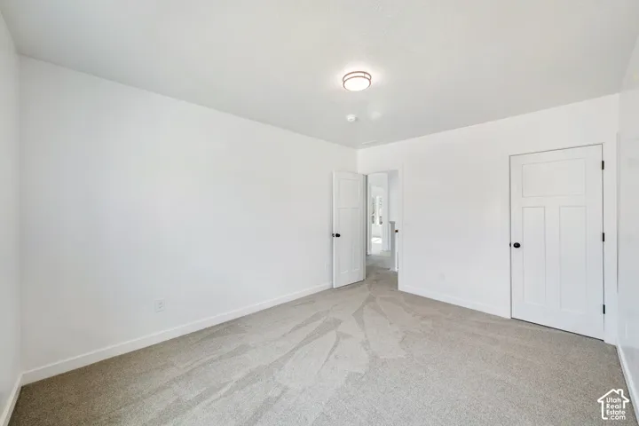 Neutral wall color, carpeted flooring, overhead lighting, and white paneled doors with dark hardware