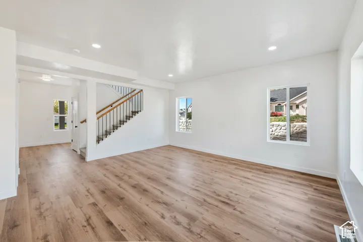 Spacious interior featuring wood-finish flooring, recessed lighting, and white walls