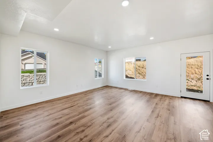 Wood-finish flooring, recessed ceiling lighting, multiple windows, and a glass-paneled door