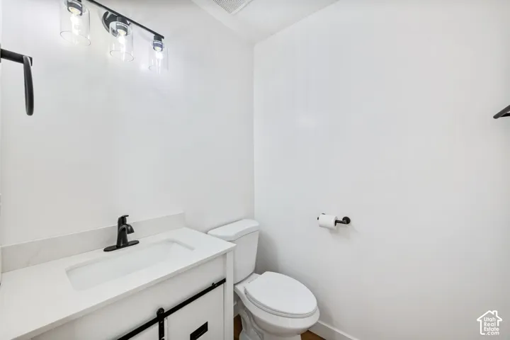White vanity with a single basin sink, matte black faucet, and white countertop