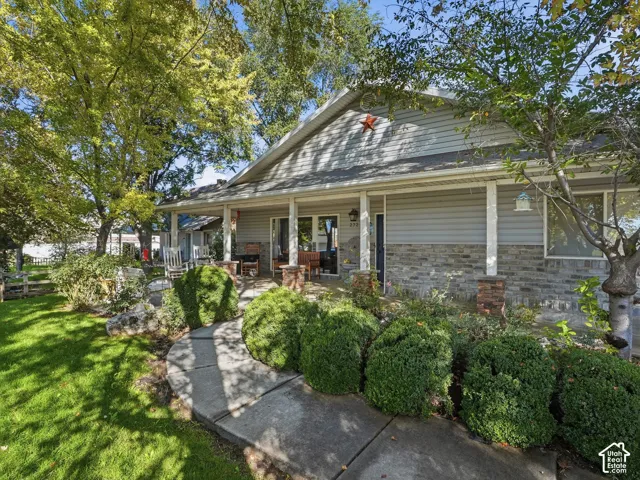 Front exterior with a covered porch, siding and stone veneer facade, and mature landscaping