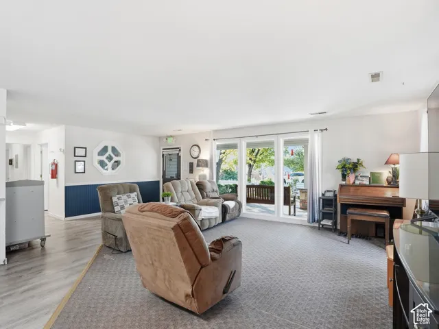Carpeted flooring, wood-finish flooring, white walls, full-height windows, and a sliding glass door