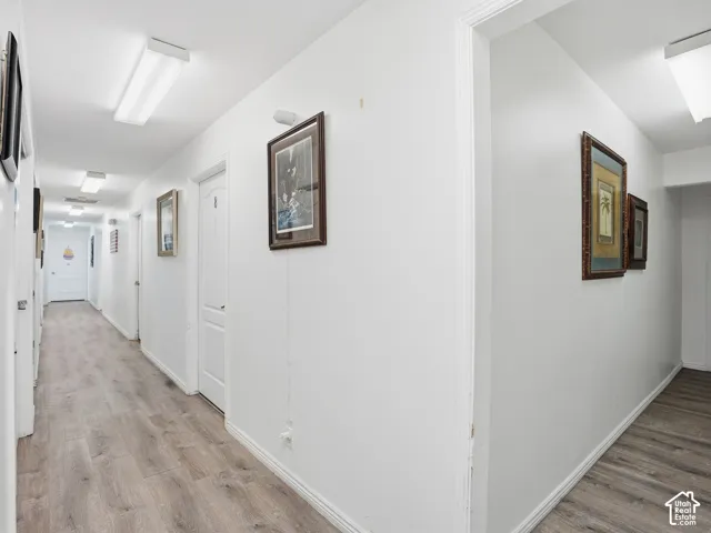 Hallway featuring wood-finish flooring, white walls, and recessed lighting fixtures