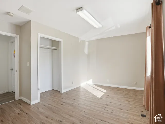 Wood-finish flooring with neutral wall tones and a built-in closet rod