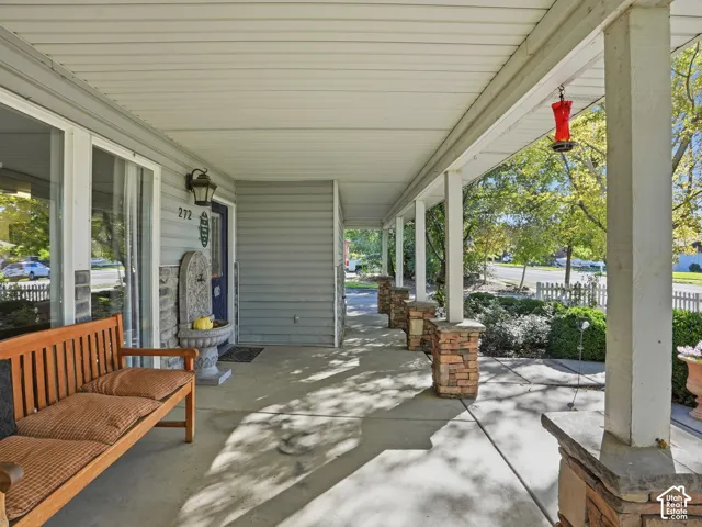 Covered front porch featuring a stone water fountain, multiple support columns with stone bases, and a sliding glass door entry