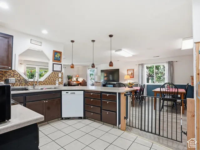 Kitchen featuring white tile flooring, brown cabinetry, a tile backsplash, and an octagon-shaped window