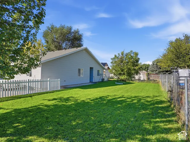 Expansive green lawn, white picket fencing, chain-link fencing, mature trees, and siding exterior