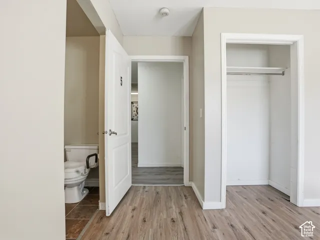 Wood-finish flooring throughout, white interior doors, and a built-in closet with shelving and hanging rod