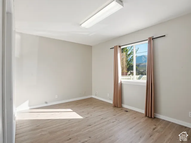 Wood-finish flooring, neutral wall paint, and a large window with white trim