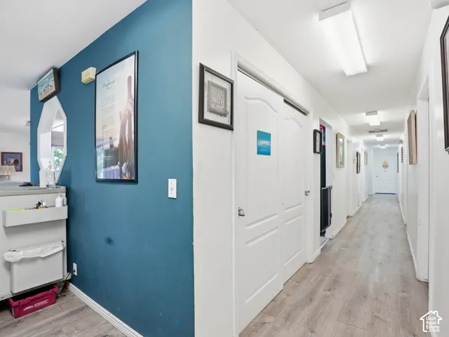 Hallway featuring wood-finish flooring, white paneled doors, and recessed lighting