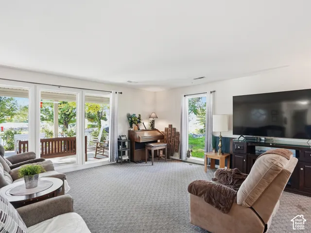 Carpeted living area with multiple windows, a built-in media console, and a direct entrance to an outdoor patio