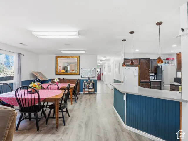 Open-concept area featuring wood-finish flooring, a kitchen island with beadboard paneling, and a full kitchen with dark wood-finish cabinetry