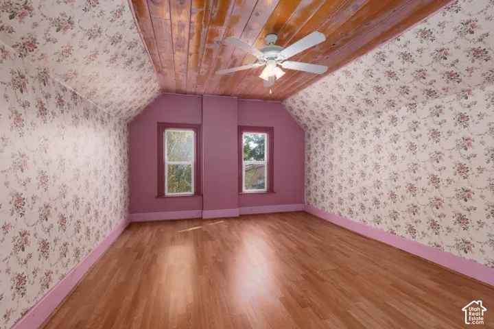 Wood-finish flooring with a wood-plank ceiling, two windows, and a ceiling fan