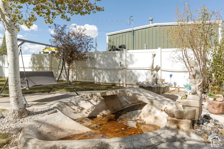 Backyard with a concrete water feature, established trees, and a privacy fence