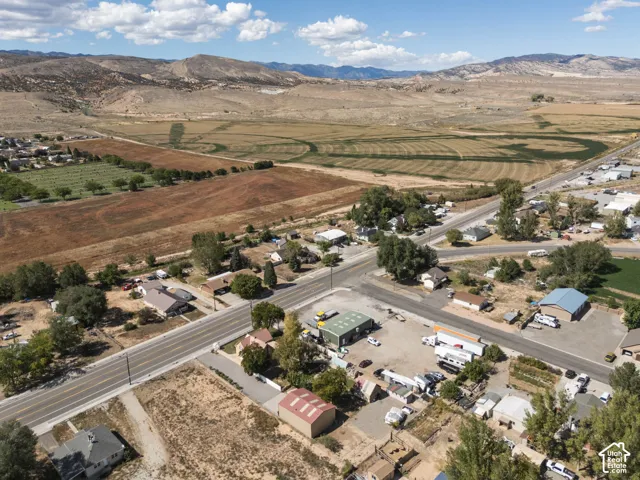 Expansive rural setting with mountainous backdrop, featuring varied terrain including cultivated fields and undeveloped land