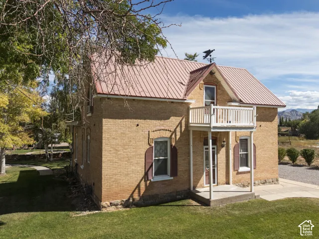 Brick exterior with a red corrugated metal roof, a second-story balcony, and a covered porch
