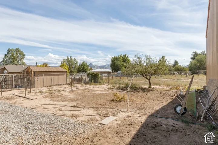 Expansive outdoor area featuring a gravel pad, chain-link fencing, and mature trees