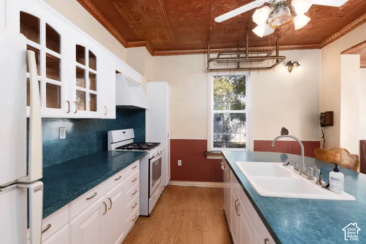 Kitchen featuring white cabinetry, a built-in gas range, a white double-basin sink, wood-finish flooring, and a decorative ceiling