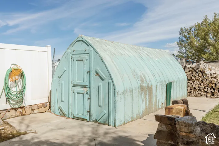 Quonset hut-style structure with a front access door and side access panel, situated on a concrete slab