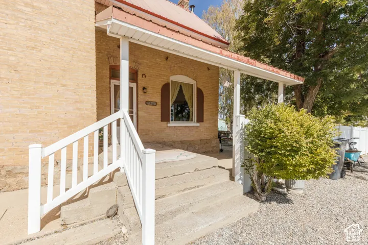 Brick exterior with a covered porch, white railing, and decorative window shutters