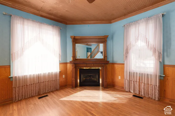 Wood-finish flooring, wood paneling, wood-paneled ceiling, decorative wooden fireplace mantel with mirror, gas fireplace insert