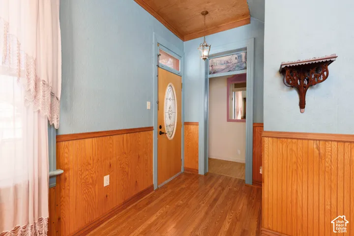 Hardwood-style flooring, wainscoting, and a decorative wall shelf