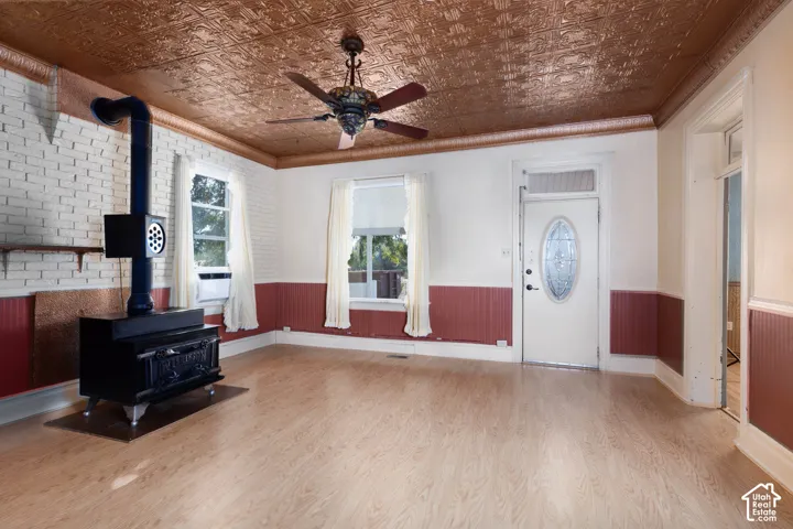 Embossed ceiling, wood-finish flooring, white brick wall, decorative wood stove, and a front entry door with an oval glass insert