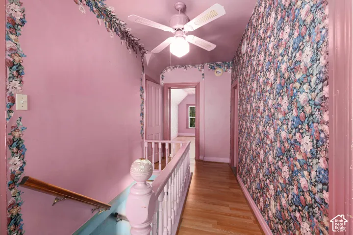 Hardwood flooring, painted walls, wallpapered accent wall, painted trim, and a ceiling fan with integrated lighting