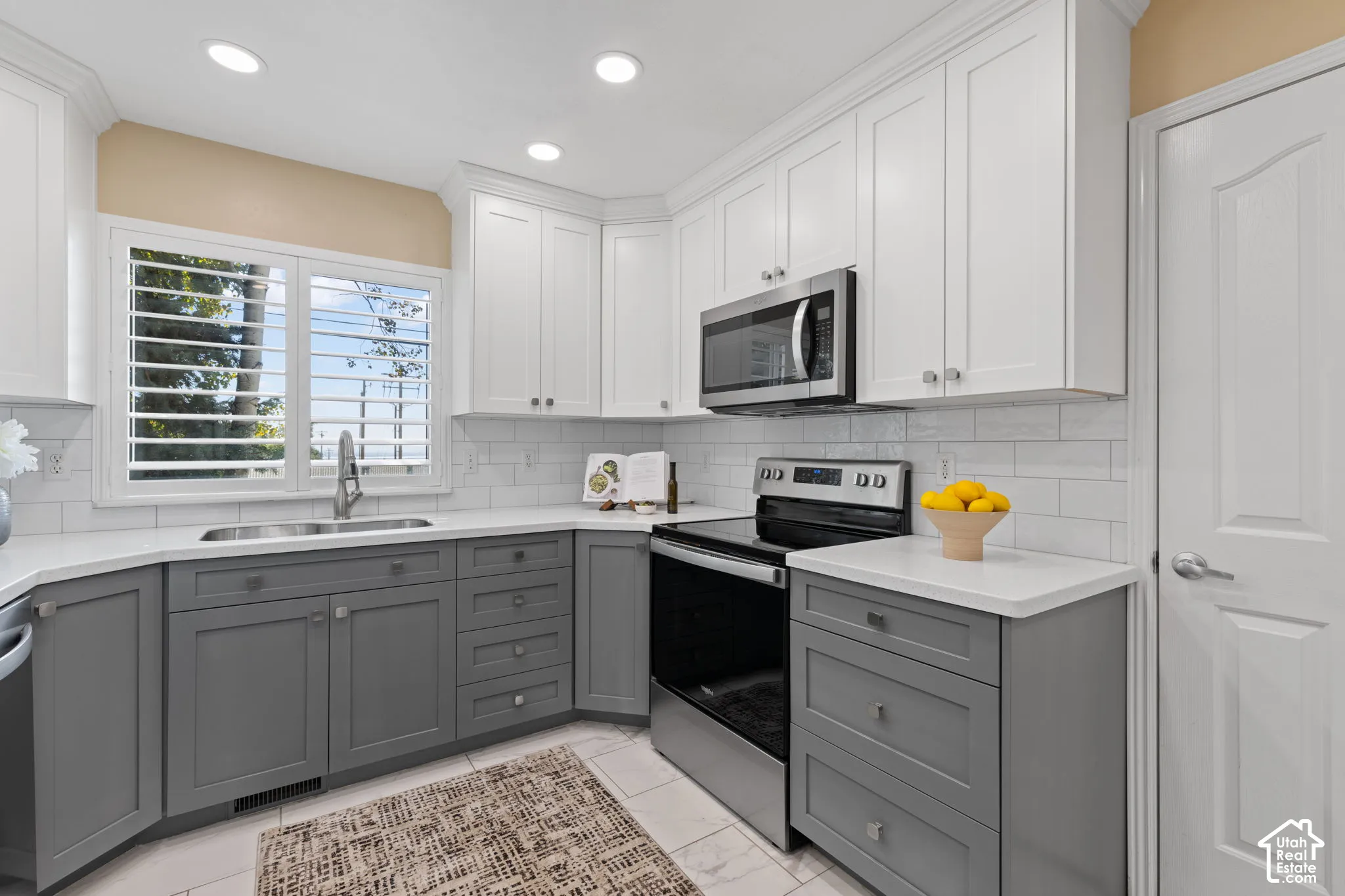 Kitchen featuring two-tone cabinetry, stainless steel appliances, white subway tile backsplash, and recessed lighting