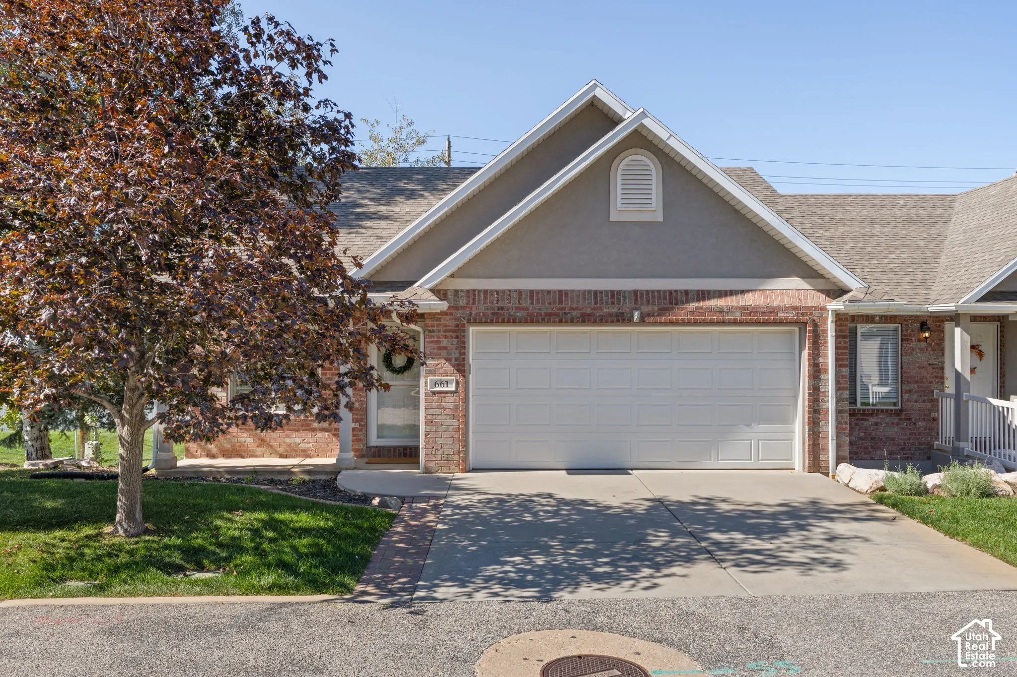Brick and stucco exterior with a white garage door, gabled roofline, and front porch