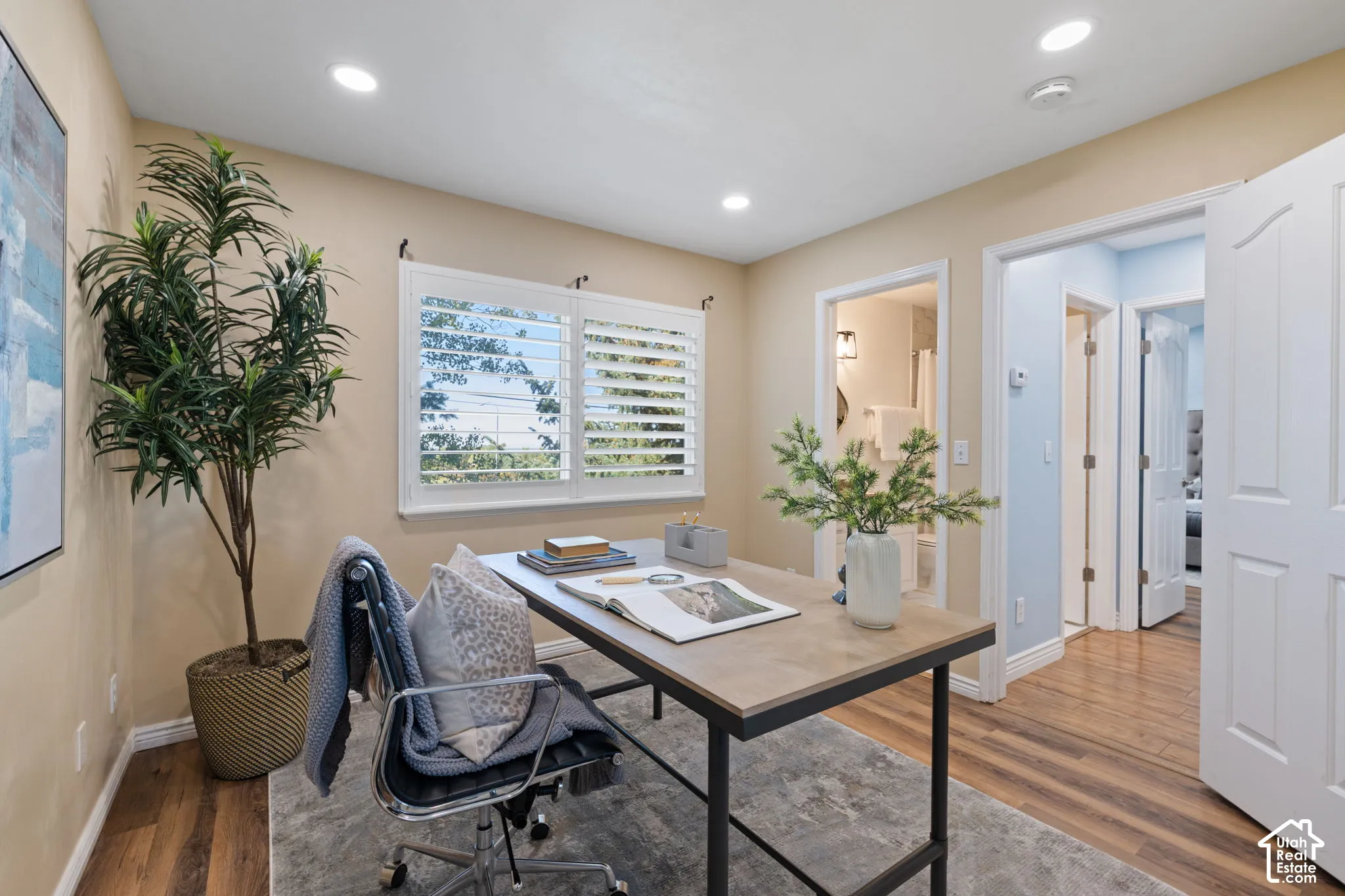 Wood-finish flooring, recessed lighting, and a window with white shutters