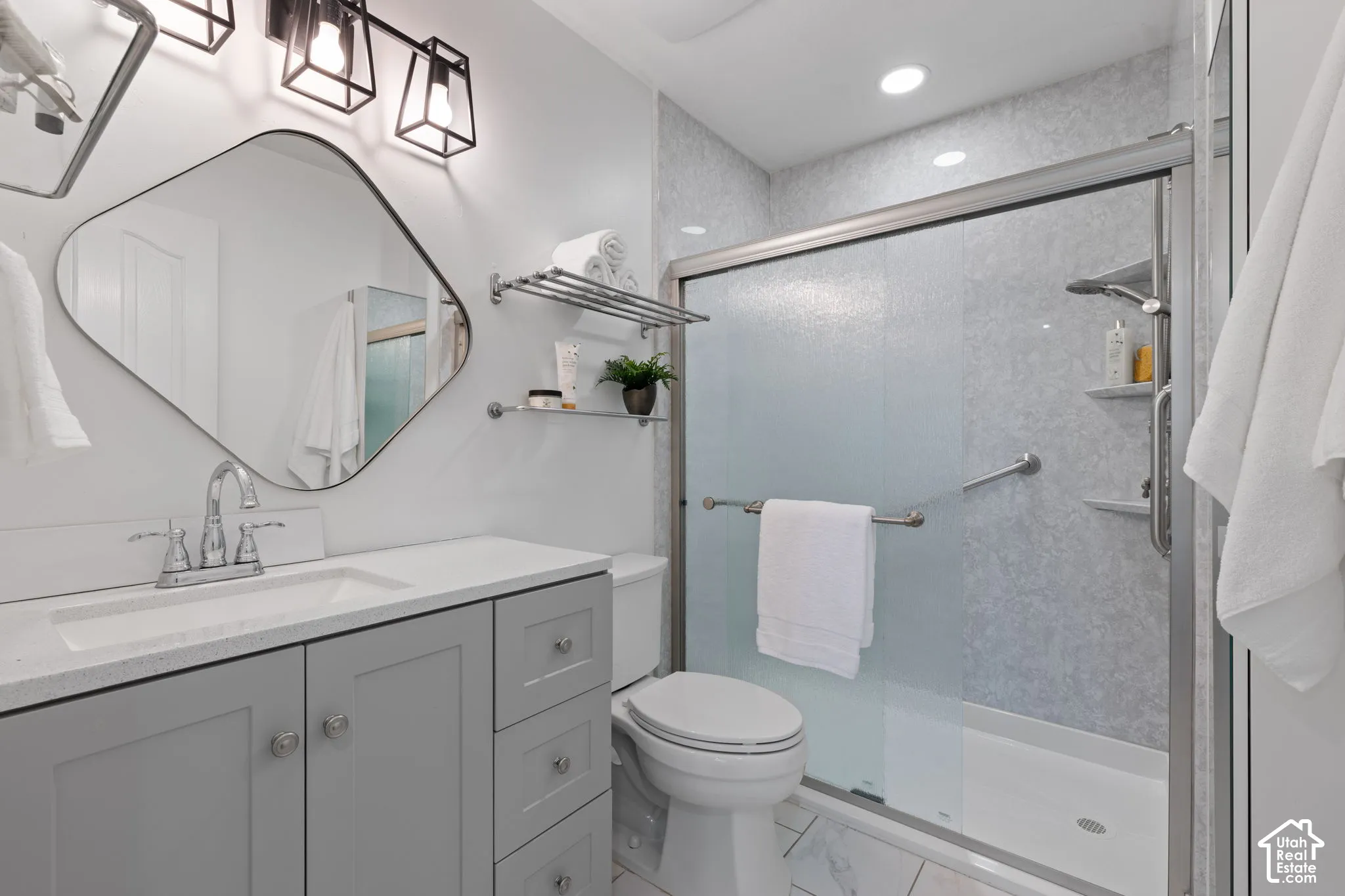 Spa-inspired bathroom featuring a floating vanity with quartz countertop and integrated sink, frameless glass shower enclosure with tile surround, and polished chrome fixtures