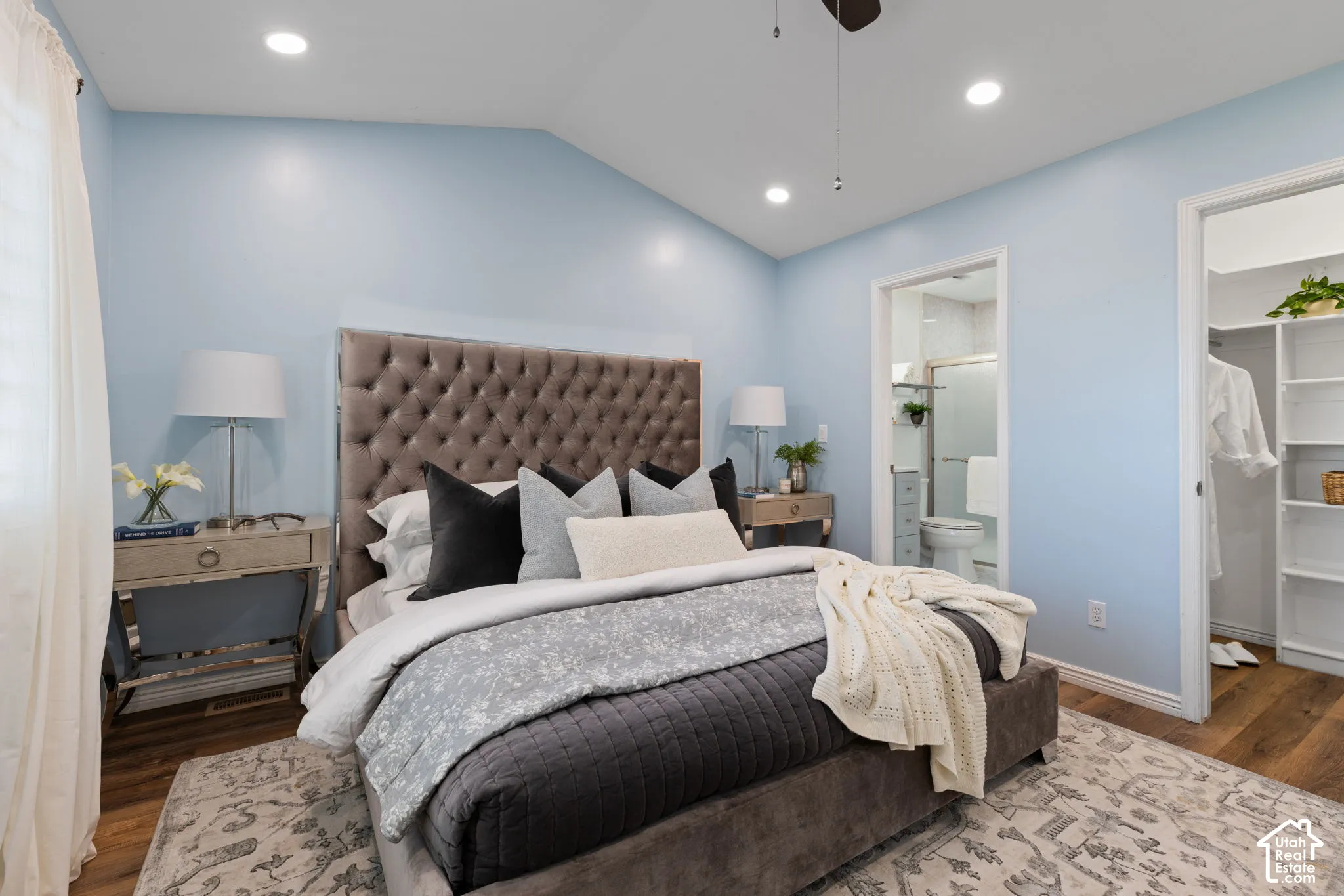 Primary bedroom suite featuring a tufted upholstered headboard, recessed ceiling lighting, and soft blue accent walls